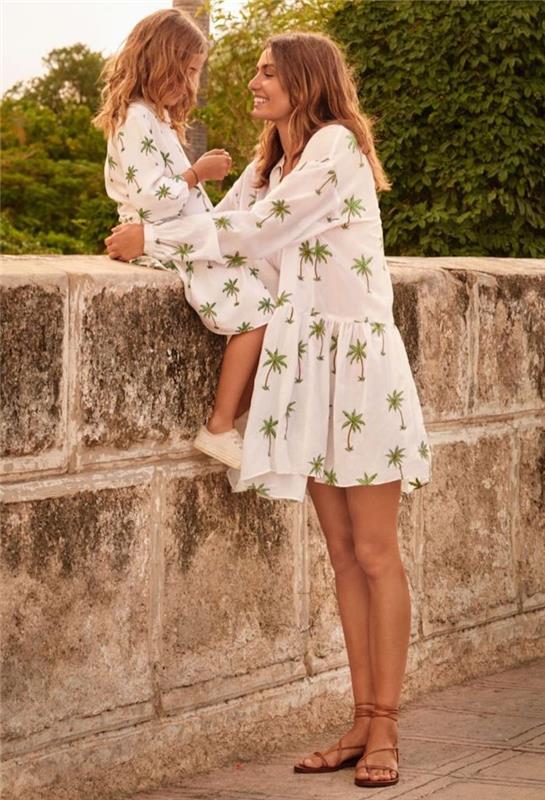 Yeşil palmiye ağaçları ile aynı beyaz elbiseyi giyen anne ve kızı, eşleşen anne kızı kıyafeti tatil fotoğrafı, anne-kız kıyafet seçimi