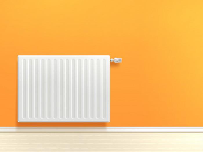balta šildymo instaliacija ant oranžinės sienos šviesių parketo grindų