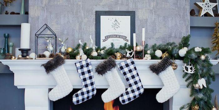 Noel çorap şöminesi bir çelenk önünde asılı beyaz ve lacivert temalı çoraplarda bir dekorasyon