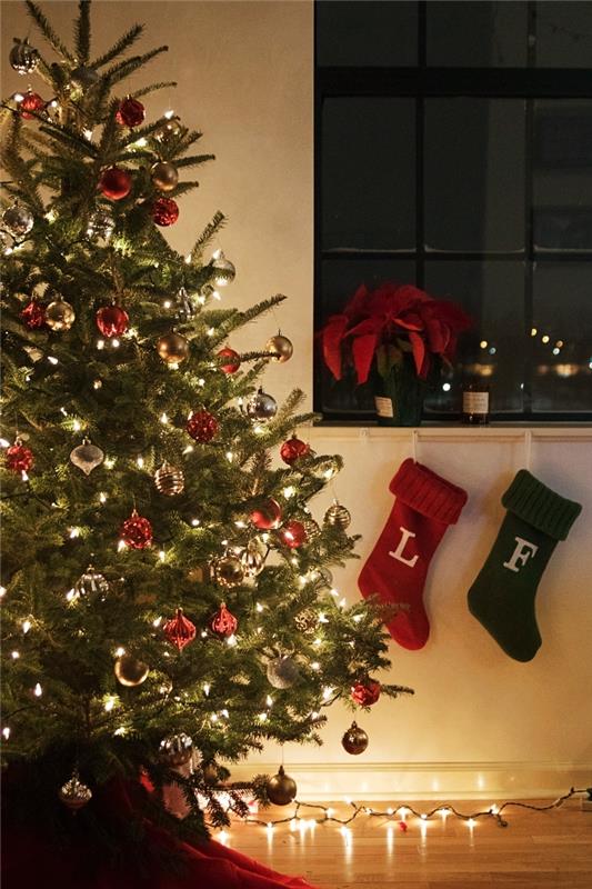 linksmų Kalėdų įvaizdis, kalėdiniai tapetai su dideliu natūraliu medžiu, papuošti raudonais ir auksiniais ornamentais jaukioje svetainėje