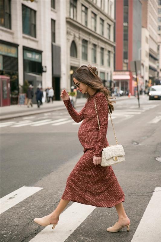 ideja za obleko nosečnice jesen 2019, nosečnica v dolgi rjavi obleki z bež čevlji in belo torbico
