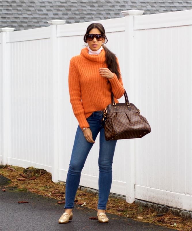 oranžna ženska oblačila trend zima 2020, model fit kavbojk v kombinaciji z oranžnim vrhom ter zlato -rjavimi dodatki