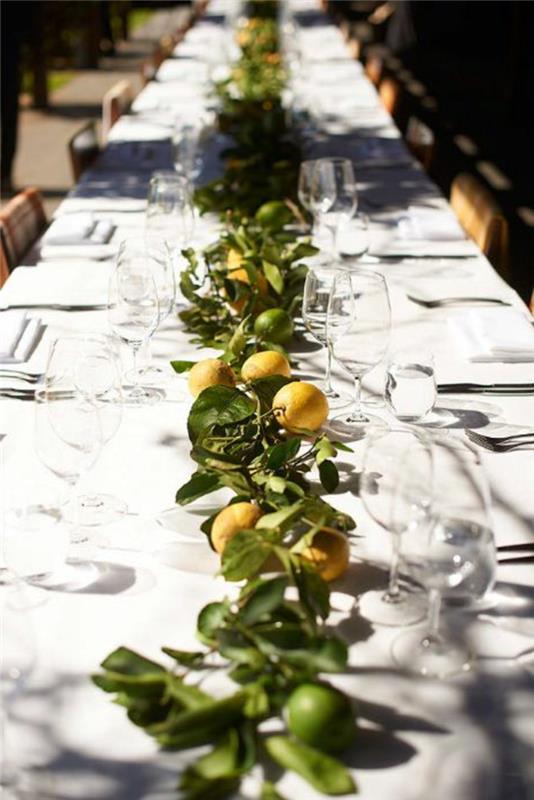 stalo bėgikas su citrinomis ir lapais, kaimiškas vestuvių stalo dekoravimas, balta staltiesė, medinės kėdės