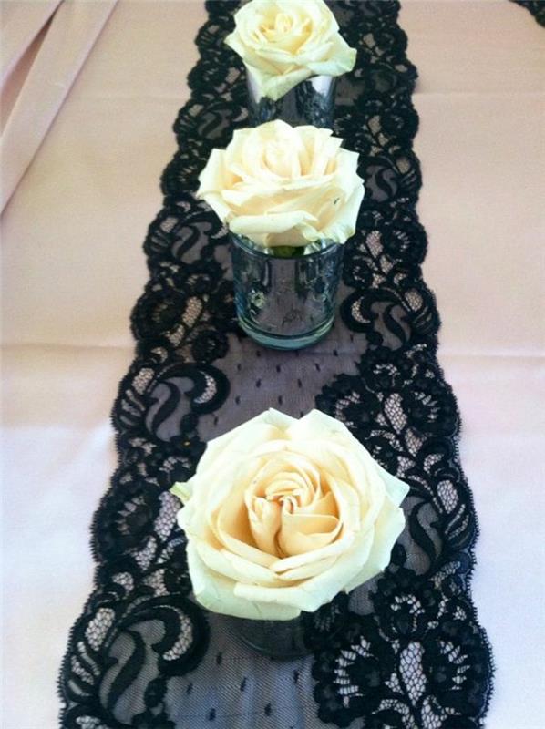 dekoratyvinis valgomojo stalas, juodas nėrinių stalo bėgikas, vazos su kaimiškomis baltomis rožėmis