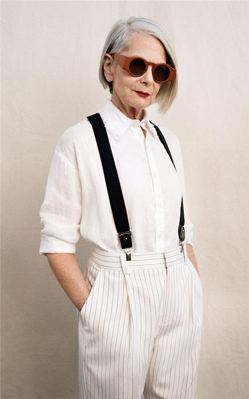balti marškiniai ir baltos kelnės su plonomis juodomis juostelėmis ir petnešomis idėja modernios išvaizdos moteris 60 metų kvadratinio kirpimo moteris 60 metų