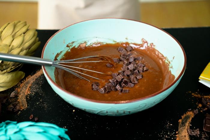 šokoladinių keksiukų receptas, šokoladas supjaustytas kubeliais, įmaišytas į miltų mišinį, sumaišytas mėlyname keramikiniame dubenyje