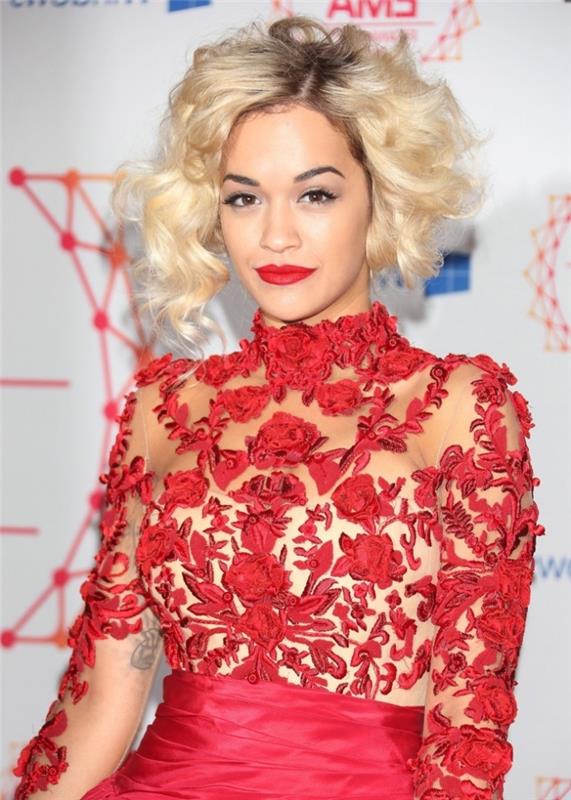 kırmızı rujlu makyaj, koyu renkli kökleri olan kısa sarı saçlı Rita Ora ve kırmızı elbise