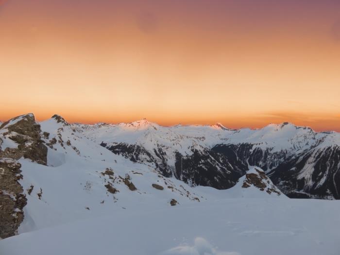 dağlarda gün batımının muhteşem fotoğrafı, turuncu gökyüzü ve karla kaplı tepeler ile karlı manzara