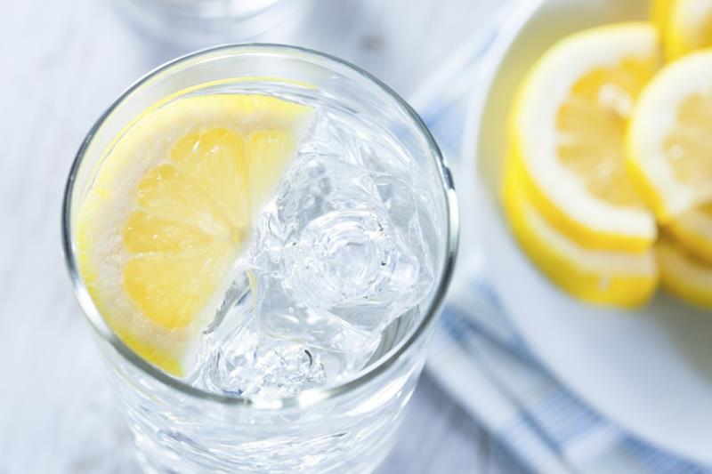 citrina naudinga stiklinei vandens su citrinos griežinėliu ir ledo kubeliais