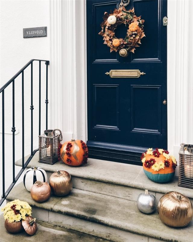koyu mavi ön kapı ve beyaz ev cephesi, meyvelerden yapılmış çelenk ve Cadılar Bayramı için kuru yapraklar