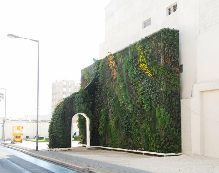 beyaz kapılı kemerli dış yeşil duvar, yeşil, sarı ve kahverengi yerleştirme, dikey işleme, beyaz duvarlı bir binanın tamamlayıcı unsuru