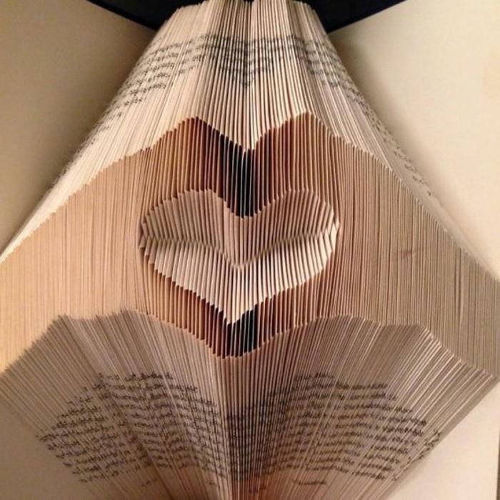 odprta knjiga s starinskimi stranmi, prepognjena tako, da ustvari dve roki in oblikuje srce