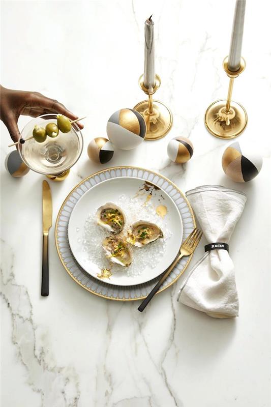 kako narediti novoletno dekoracijo mize z zlatimi svečami, belimi in zlatimi krožniki, okrasnimi kroglicami v zlati, črni, sivi in ​​beli barvi