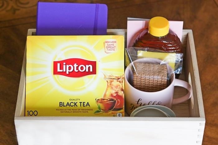 meistrų dovanų dėžutės pavyzdys su arbatos puodeliu, sausainiais, mokyklos dienoraščiu ir buteliu medaus