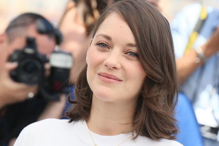 frizura srednje dolžine z rahlo kodrastimi stranskimi šiškami, pričeska Marion Cotillard z lasmi v naravni senci