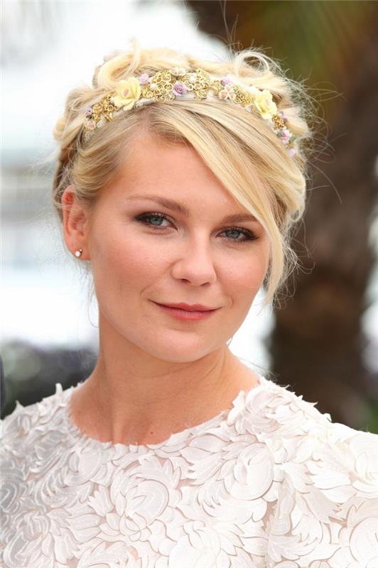 gėlių karūna Kirsten Dunstt plaukuose, balta nėrinių suknelė