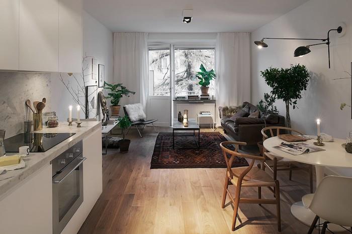 kuhinja odprta za skandinavsko dnevno sobo s sivim kavčem, orientalsko preprogo, boemskim elegantnim stolom, belo kuhinjo z marmornim škropljenjem