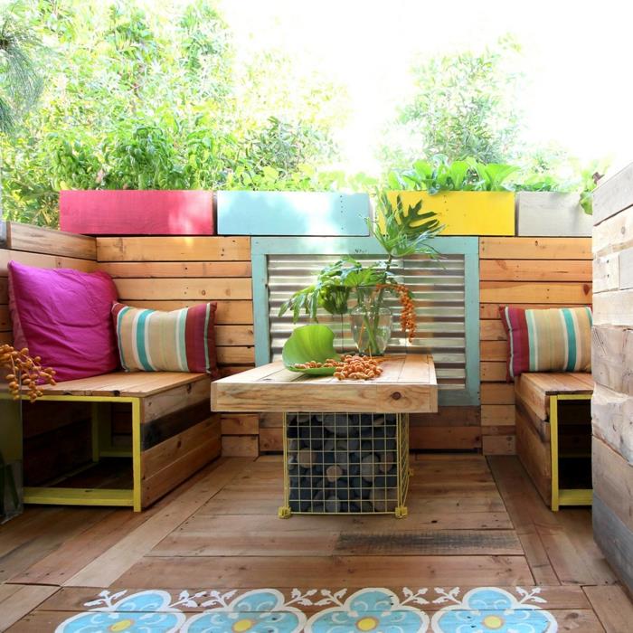 terasos zona su padėklų sodo baldais, padėklų stalas ir sofa, keturi stačiakampiai vazonai su fuksijos, pastelinės mėlynos, geltonos ir dramblio kaulo spalvos augalais