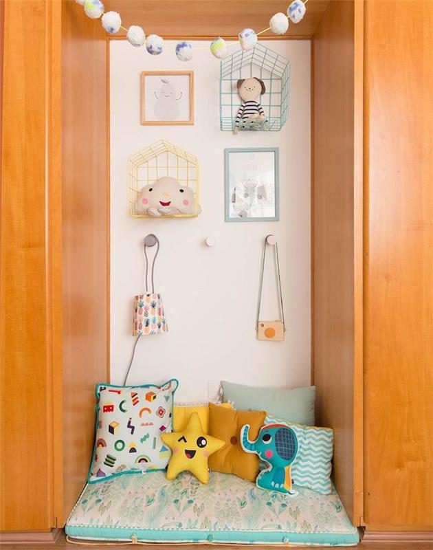 sienų niša kaip „Montessori“ veiklos zona arba vaikų skaitymo zona su čiužiniu ant grindų, daugybė vaikiškų pagalvėlių, vaikiška sienų apdaila
