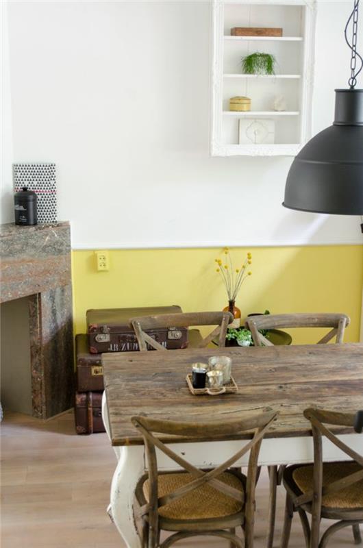 sarı ve beyaz hardal rengine boyanmış iki tonlu duvara sahip rustik tarzda bir yemek odası, ham ahşap mutfak masası