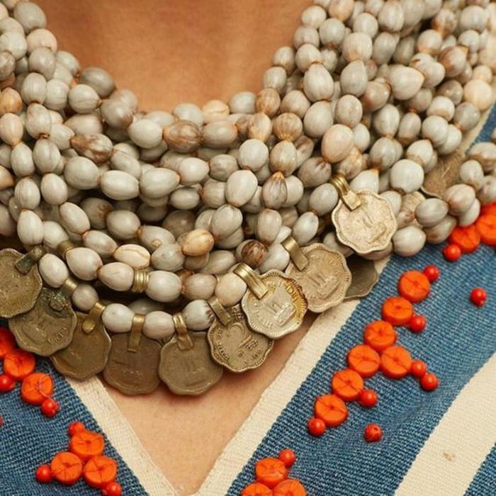Afrikos karoliai baltos spalvos su smulkiais elementais, kurie atneša laimę, brangakmenis, dėvėtas su afrikietiškais drabužiais, papuoštas mažais oranžiniais mediniais karoliukais