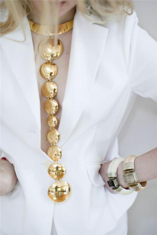 ekstravaganten in dolg dragulj z zlatimi kovinskimi kroglicami, elegantnimi večernimi šok detajli, dragulji, oblečeni čez klasično belo jakno