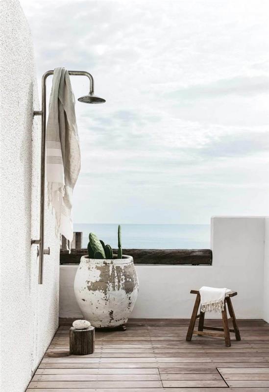 minimalističen dizajn v zunanji kopalnici na terasi z belimi stenami in lesenimi deskami s kovinsko prho