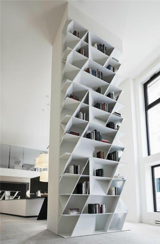Visiškai balta kolonėlės formos skiriamoji lentyna, aukštos įstrižainės knygų lentynos, grindys padengtos baltu parketu
