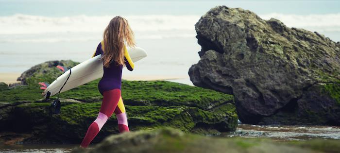 Kalifornijska rjavolaska balayage, surf obleka z rdečimi in rožnatimi gamašami ter vijolično rumenim vrhom, bela deska za deskanje