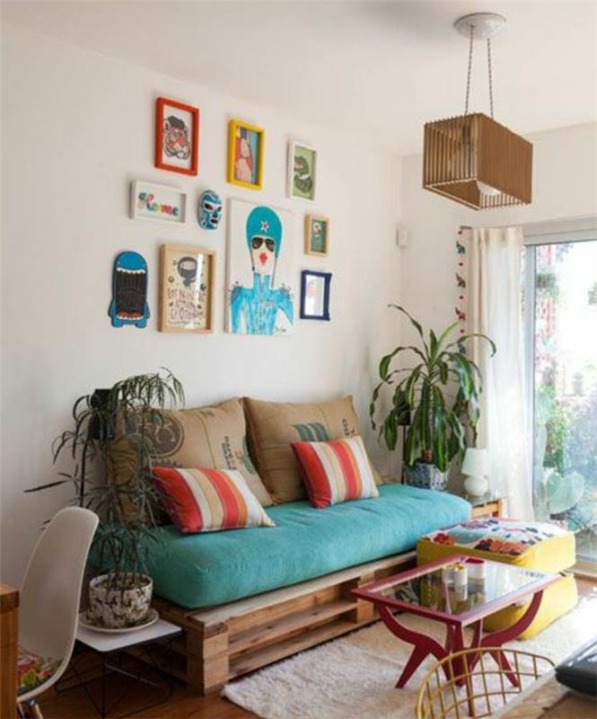 vazoniniai augalai ir spalvingi įrėminti kūriniai, šalia „pasidaryk pats“ padėklų sofos, dekoruotos didele turkio spalvos pagalve ir keliomis pagalvėlėmis