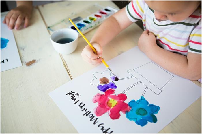 Vaikas, kuris nuspalvina paprastą gėlių vazono piešinį, mamos dienos dovaną, šaunų mamos dienos užsiėmimą