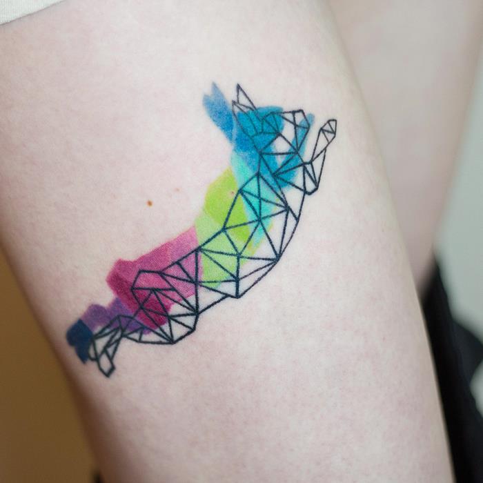 geometrijski zajec v mavrični barvi, tetovaža stegen, sveta tetovaža, zamegljeno ozadje