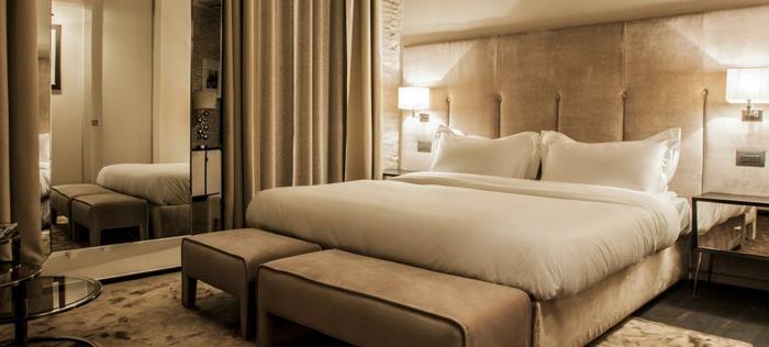 romantik bir yatak odasında krem ​​rengi dekorasyon, yumuşak yatak başlığı, bej halı, bej çekyat