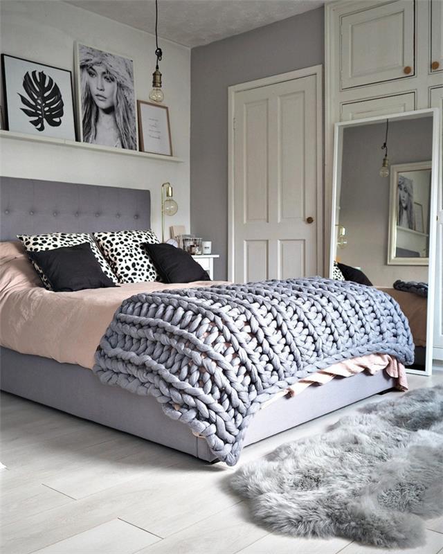 didelė kokono lova, pilkas kailio kilimas, dekoratyvinės pagalvėlės, kokios spalvos miegamajam, baltos spalvos durys
