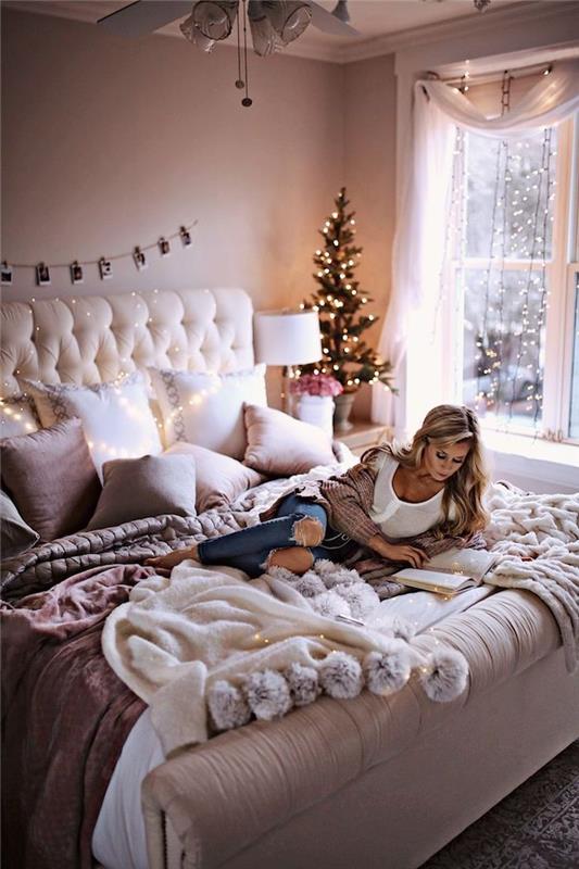 romantiško miegamojo dekoro pavyzdys su paminkštinta galvūgaliu, purpurinėmis ir baltomis pagalvėlėmis, minkštu lovos užtiesalu, dekoratyvine lengva girlianda, žiemos Kalėdų miegamojo dekoru