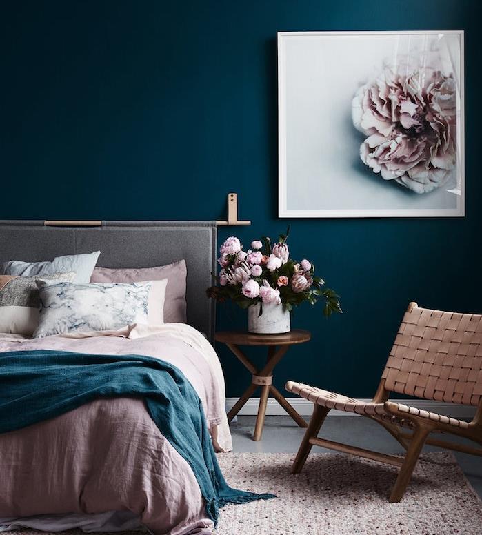 slikanje spalnice za odrasle temno modre barve, roza, modro in belo posteljnina, naslanjač, ​​bakrena mizica s šopki rož v vazi, okvir za slikanje cvetja