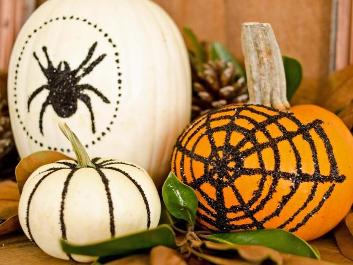 lengvai pagaminami Helovino papuošimai, balti arba oranžiniai moliūgai su juodos spalvos blizgučiais, kurie yra voratinklio formos