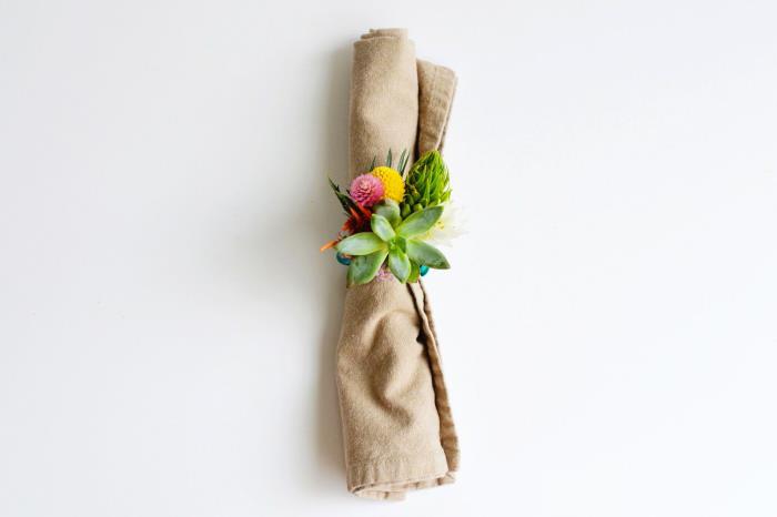 lininis audinys susuktas ir papuoštas servetėlės ​​žiedu su gėlėmis, pasidaryk pats dekoras