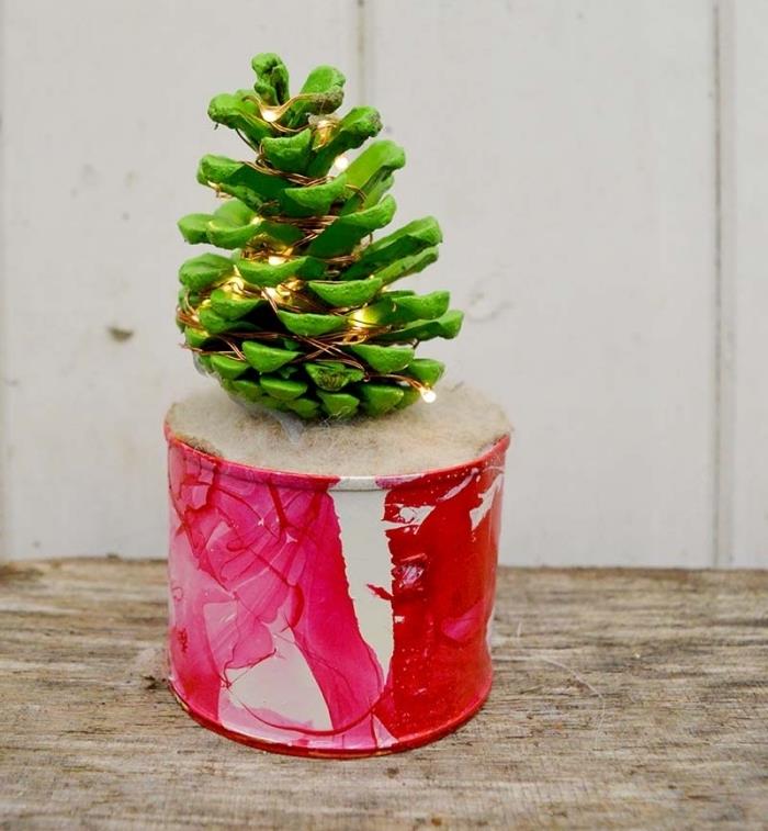 enostavna božična ideja DIY, ročno izdelan model mini božičnega drevesca v zeleno pobarvanem borovem storžu, okrašenem s svetlim vencem