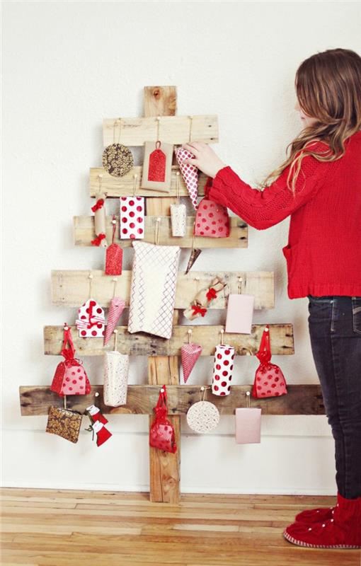 medinė eglė, pagaminta iš sukryžiuotų lentų, papuošalų ir dovanų, įvyniotų į raudoną ir baltą dekoratyvinį popierių, baltos dovanos su raudonais taškeliais