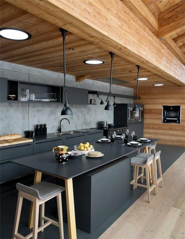 soba s pohištvom v ogljeno sivi barvi, kuhinjo prebarva, strop z masivnimi lesenimi tramovi, tla s sivim parketom, barski stoli v pastelno sivi barvi z nogami iz svetlega lesa