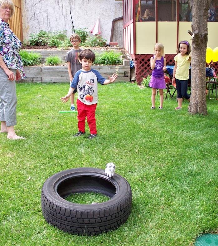 bir çocuğun beceri oyunu örneği, içi boş bir lastiğe uzaktan bir nesne fırlatma, eğlenceli bir çocuk doğum günü etkinliği fikri