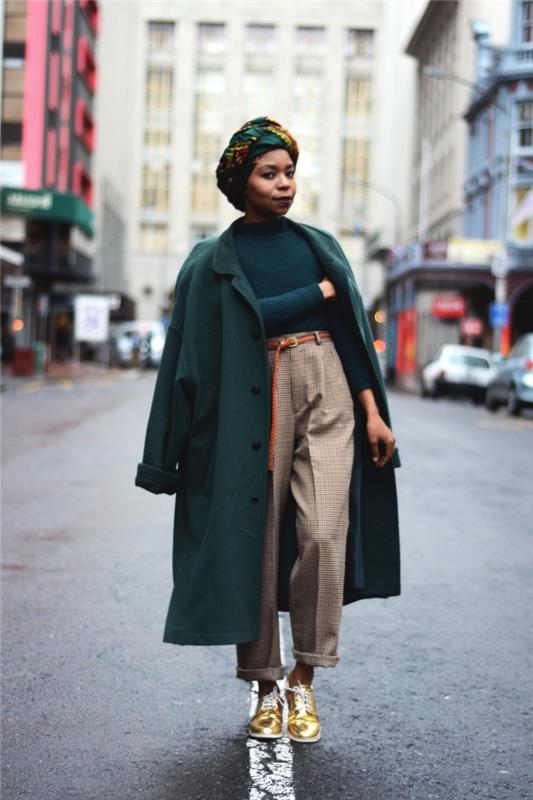 kaip dėvėti Afrikos vaško audinio turbaną su miesto prašmatnia apranga, elegantiška ir atsipalaidavusia išvaizda pritaikytose kelnėse, žaliame megztinyje ir dideliame žaliame palte