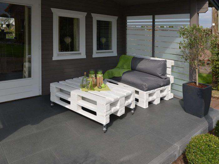 Modern pergola altında deco kaplı teras, ağartılmış palet koltuk ve tekerlekler üzerinde beyaz palet sehpa ile