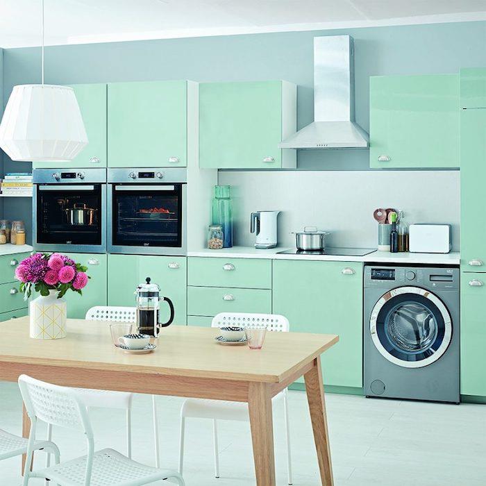 perdažykite virtuvę mėtų žalia spalva virtuvės fasadui, galinę sieną mėlyna spalva, nerūdijančio plieno prietaisus, medinį stalą ir metalines kėdes