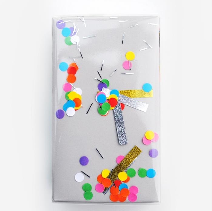 darilni ovoj, preprosta zamisel o sivem papirju in plastični embalaži s pisanimi konfeti in bleščečimi črtami pod njim