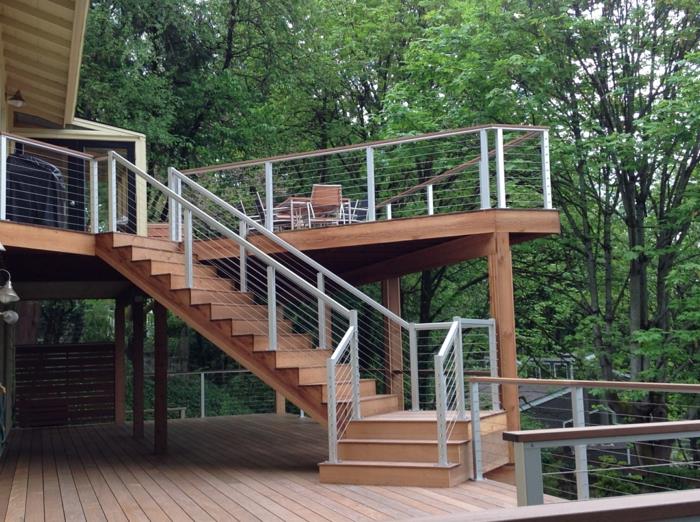 lesena terasa na podstavkih, leseno stopnišče, belo pobarvana kovinska ograja, leseno vrtno pohištvo, pogled na gozd