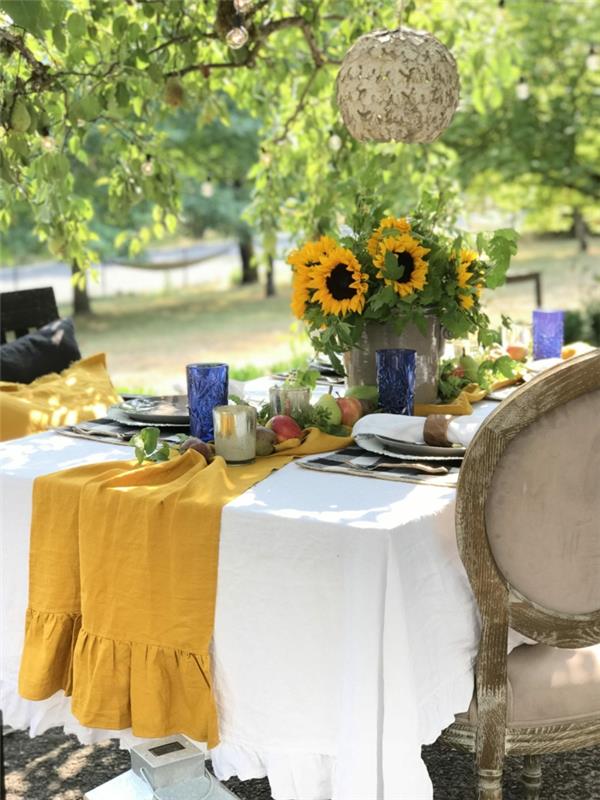 serin bahçe dekor fikri sonbahar düğün dekorasyon sonbahar masa sonbahar etkinliği sarı masa örtüsü ve ayçiçeği cam vazo