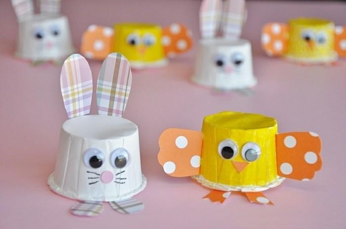 enostavne otroške obrti, zajčki in piščančji okraski, narejeni iz majhnih papirnatih skodelic v beli in rumeni barvi, okrašenih s pisanim papirjem in lepljivimi očmi