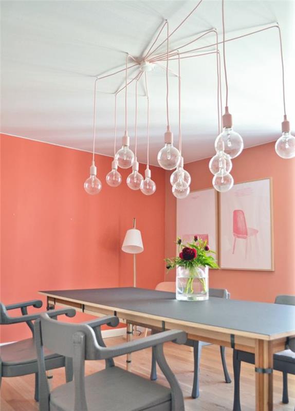 koralna barva, beli strop, več visečih žarnic, sivo pobarvana lesena miza, koralne stene